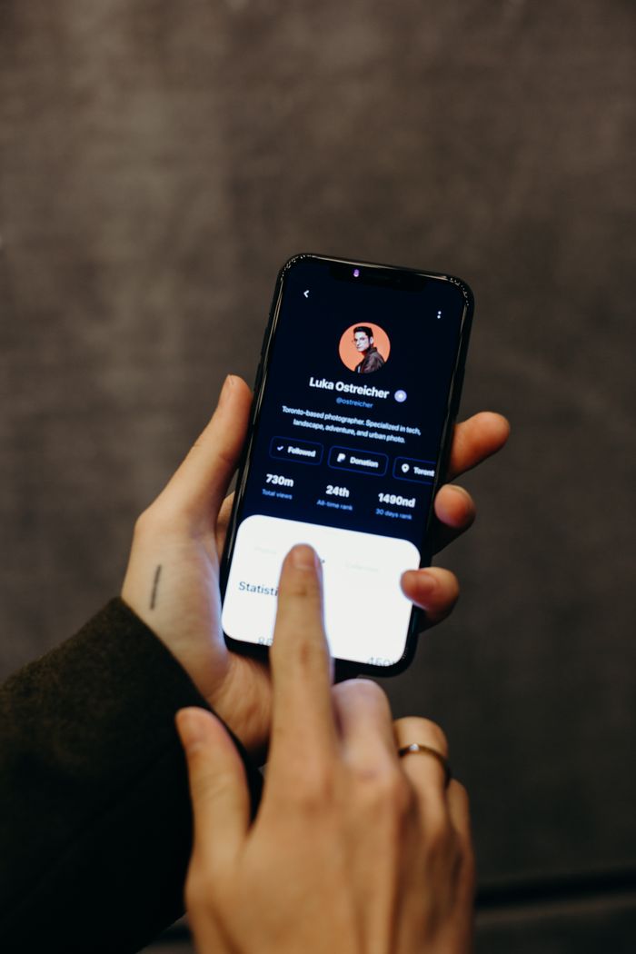 Hands holding a smartphone displaying a social media profile interface. Technology and modern connections.